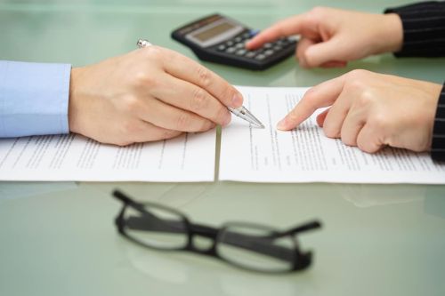 businesswoman is reviewing document with tax consultant and making calculations