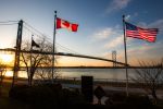 The Ambassador Bridge linkink Detroit, Michigan, USA with Windsor, Ontario, Canada. The national flags of the USA and of Canada are notable in the foreground.